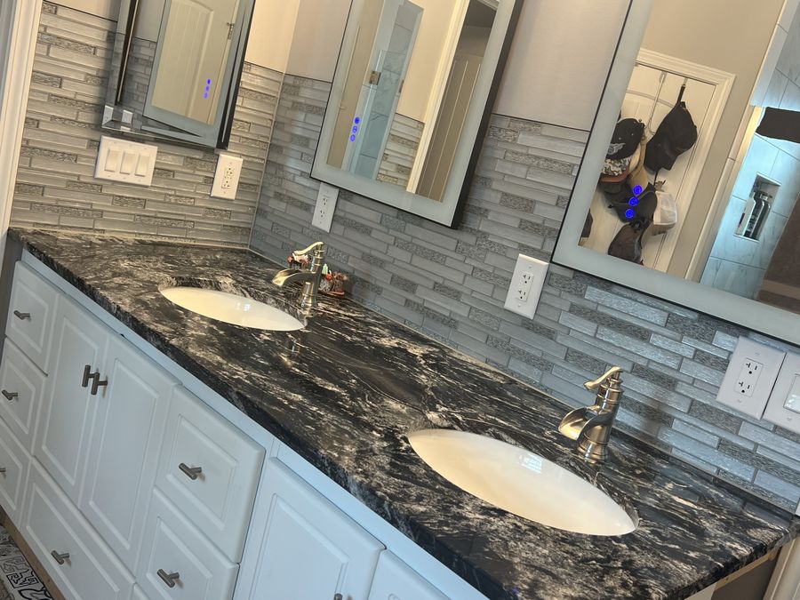 Double vanity with linear glass mosaic backsplash and dark granite