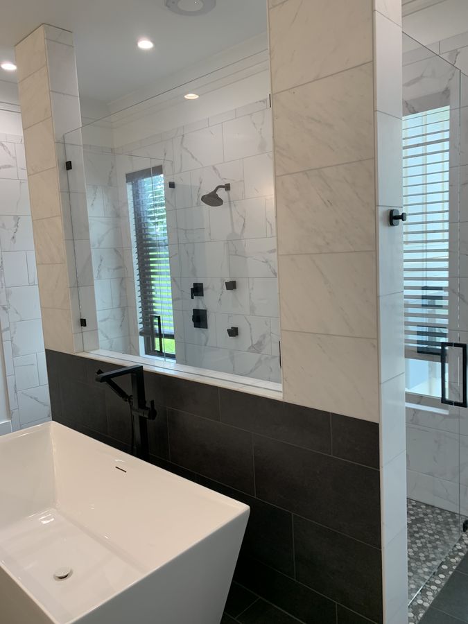 Twin glass shower enclosures either side of a tub