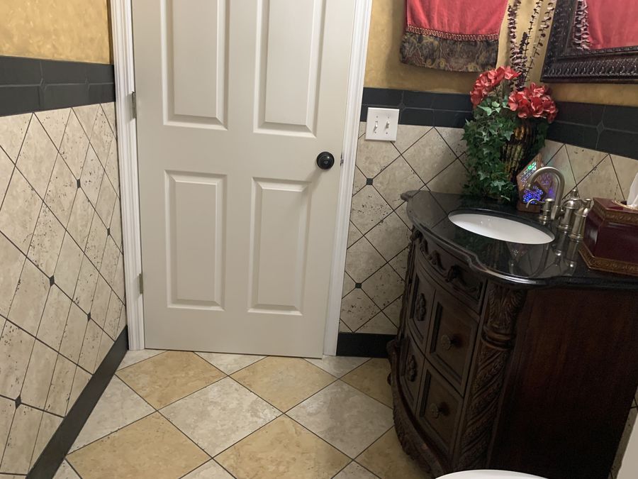 Powder room with diagonal travertine wainscot and black band